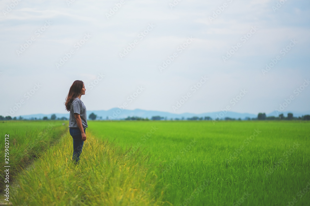 A woman standing and looking at a beautiful rice field with feeling relaxed and calm A woman standing and looking at a beautiful rice field with feeling relaxed and calm