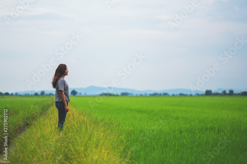 A woman standing and looking at a beautiful rice field with feeling relaxed and calm