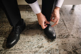 A man in a suit puts shoes on his feet.
