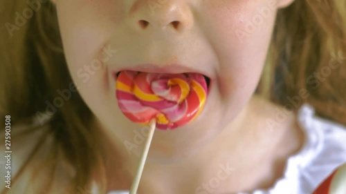 Little girl with a lollipop on a blue background. Close up portrait