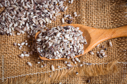 Organic black sticky rice in wooden spoons on sack photo