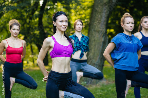 Yoga or pilates at park, group of mixed age women doing different pose while standing in morning time. Teamwork, sport, good mood and healthy life concept. Seria photo with real people models. © Iryna