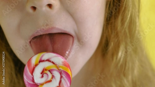 Little girl with a lollipop on a Yellow background. Close up portrait