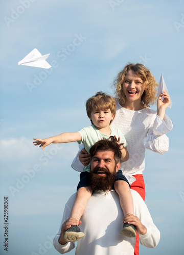 Garden party in America. Dad mom and son playing together. Family dreams of traveling. Father mother and son in the park. Mother father and son. Cute little boy is holding paper airplane.