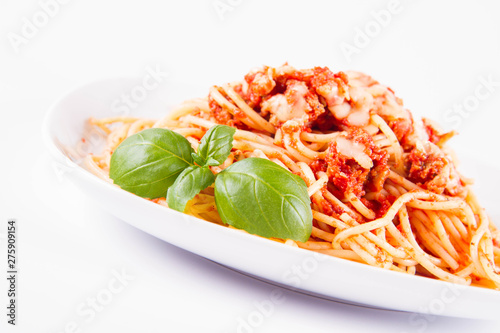 Spaghetti bolognese with melted parmesan cheese decorated with basil on a white background	