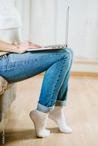 Young girl holding laptop on her legs and sits on coach