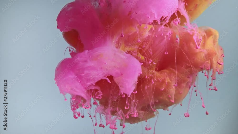 Colorful nacreous paint in water against blue background.