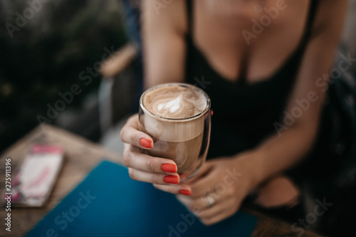 cappuccino coffee in a glass cup in the hands of a woman