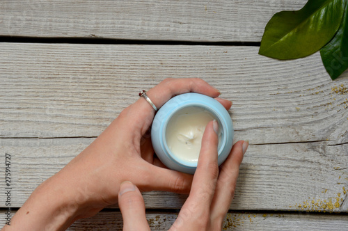 Face cream on vintage wooden white background with female hands. Anti-aging cream in the hands. Female hands holding a jar of cream. Body cream