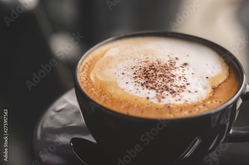 close up modern hot black coffee the cappuccino on dark background with coffee bubble foam pattern and texture in black cup looking and feel so delicious on glasses table in coffee shop.