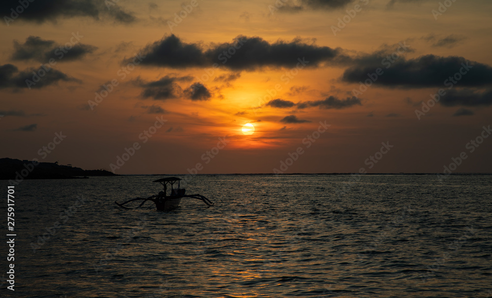 Fototapeta premium Sunset over calm ocean with balinese boat
