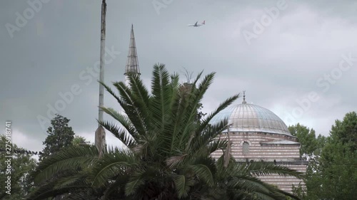 A Commercial Airplane Flies High Over A Mosque In Istanbul. photo