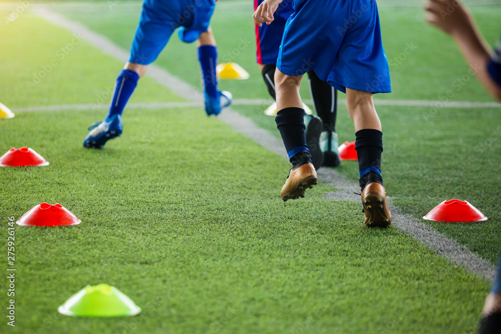 kid soccer players Jogging and jump between cone markers on green artificial turf for soccer training. kid soccer players Jogging and jump between cone markers on green artificial turf for soccer training.