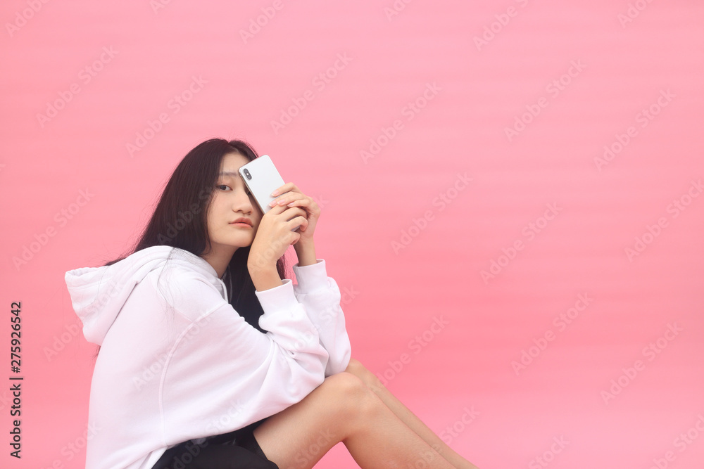 Isolated shot of pretty Beautiful Asian models over pink background for advertising concept , wears casual outfit, being entertained by friend during party Isolated shot of pretty Beautiful Asian models over pink background for advertising concept , wears casual outfit, being entertained by friend during party