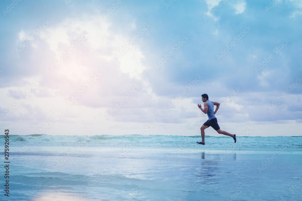 Man running athletes at the beach with sunset background.