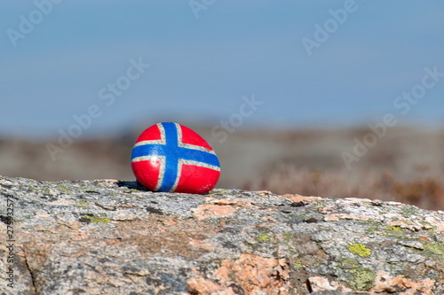 Image of the flag of Norway on a stone, between sea pebbles and seashells. Concept of Norwegian Constitution Day.  Celebrated on May 17.