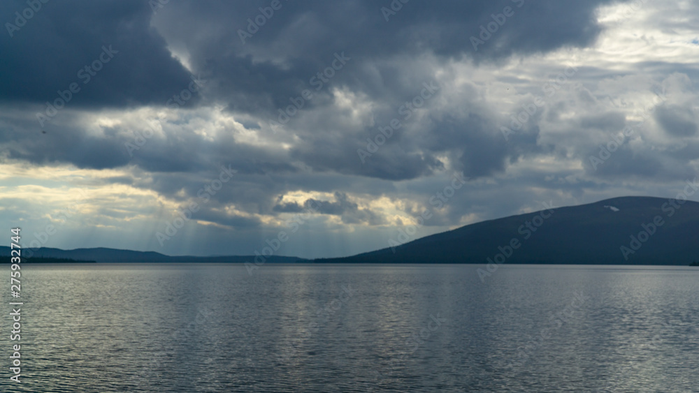 Sunlight through the clouds over the rocky northern lake