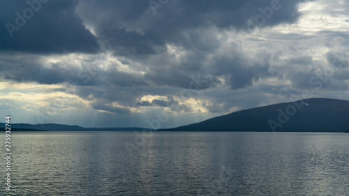 Fototapeta Naklejka Na Ścianę i Meble -  Sunlight through the clouds over the rocky northern lake