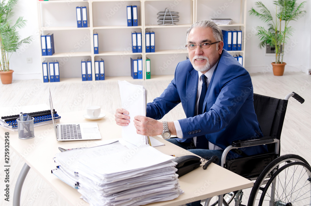 Aged employee in wheelchair working in the office Aged employee in wheelchair working in the office