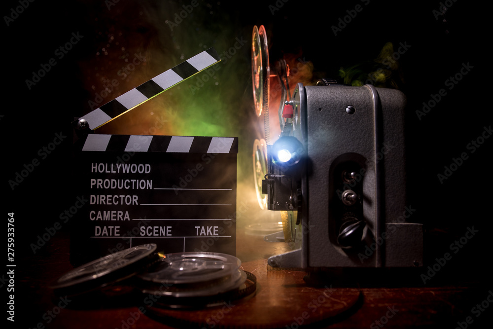 Old vintage movie projector on a dark background with fog and light. Concept of film-making. - obrazy, fototapety, plakaty 