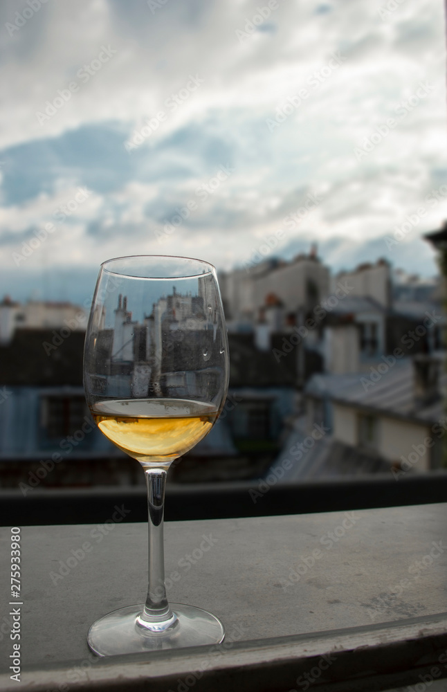 Glass of white wine on window sill with view of Paris roof tops Glass of white wine on window sill with view of Paris roof tops