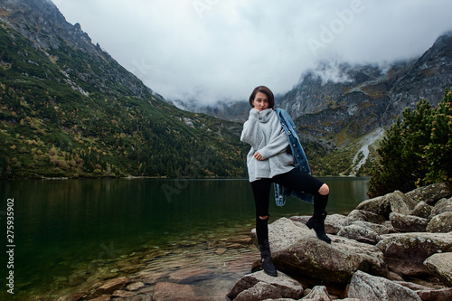 Girl staying on rocks near lake. Tatra mountains landscape in Poland  Zakopane. Mountain landscape in Eastern Europe.