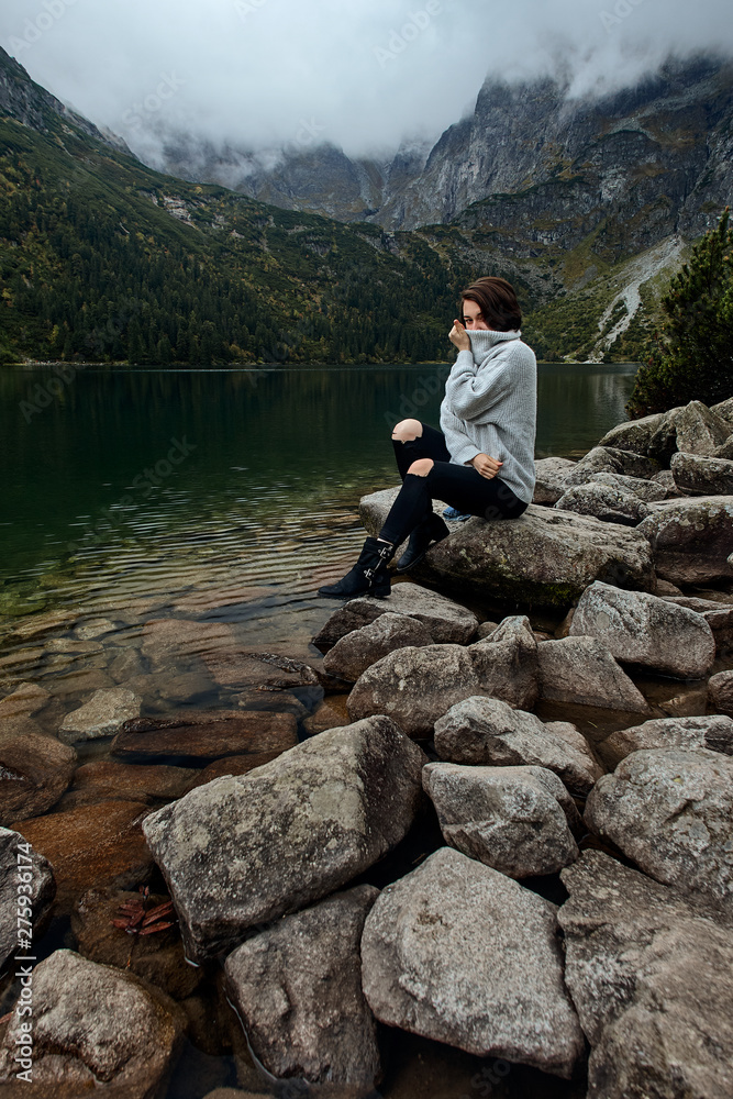 Girl sitting on rocks near lake. Tatra mountains landscape in Poland, Zakopane. Mountain landscape in Eastern Europe.
