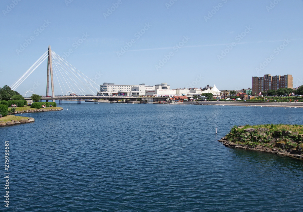 the suspension bridge and pier crossing the lake in southport merseyside with a view of the town hotels and buildings
