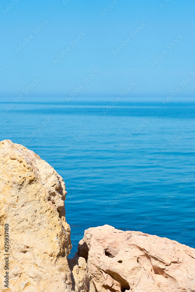                    Stones on a sea coast of Colimbari, Crete, Greece against a blue sea water. Copy space.           