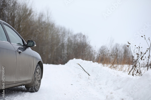 Car on a snowy winter road in fields. © alexkich