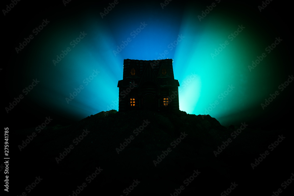 Obraz premium Old house with a Ghost in the forest at night or Abandoned Haunted Horror House in fog. Old mystic building in dead tree forest. Trees at night with moon. Surreal lights.