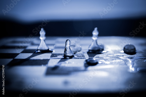 Strategy and tactics concept. Icy frosted chess figures standing on a chessboard during sunset.