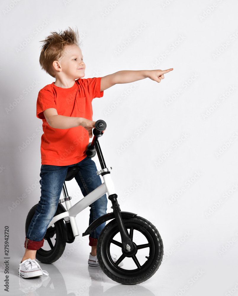 Happy kid boy sit and ride his bicycle pointing one finger on a corner biker celebrating his win in race Happy kid boy sit and ride his bicycle pointing one finger on a corner biker celebrating his win in race