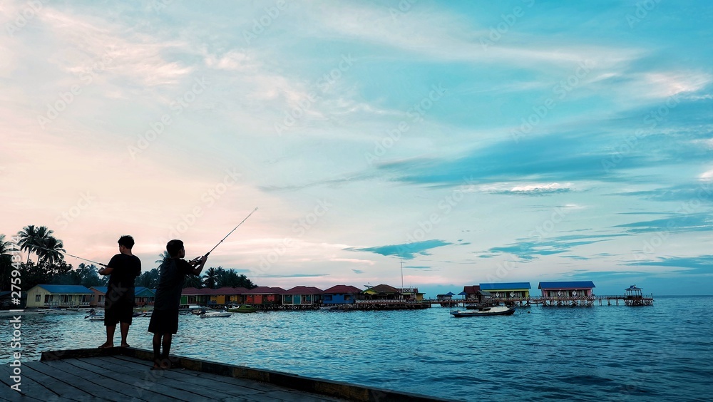 a child fishing at sunset