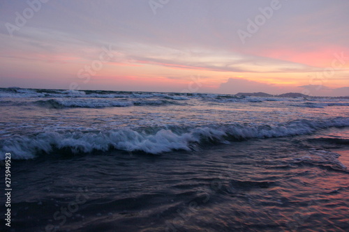 Evening sea, pink sky and people come to play in the sea.