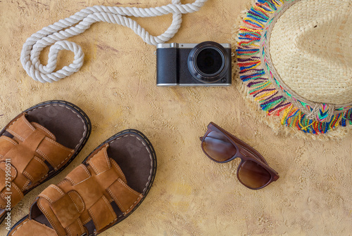 Summer lifestyle concept with hat, smartphone and camera. Summer accessories flat lay on sand background. 