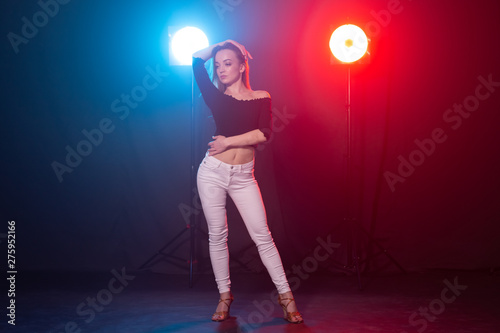Dance, grace and elegance concept - young woman dancing bachata lady style in the dark, lights and smoke