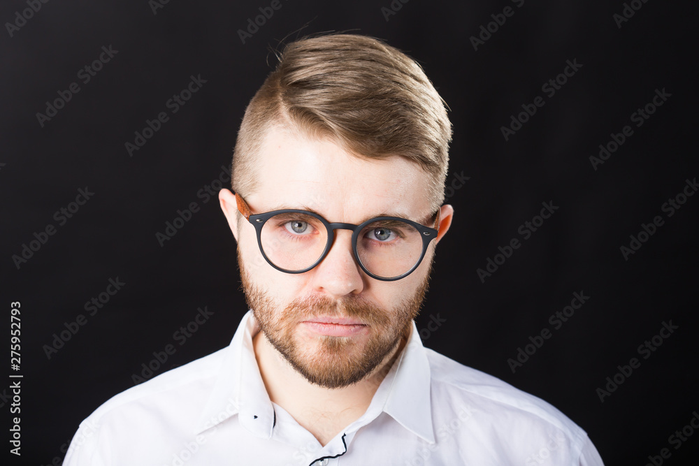 Portrait of bearded serious handsome man looking at camera isolated over black background Portrait of bearded serious handsome man looking at camera isolated over black background