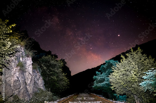 Milky way in the sky, beautiful colors and in the foreground of the railroad and the woods of the road. A colorful night photo was created in the village of Nisevac near Svrljig. photo