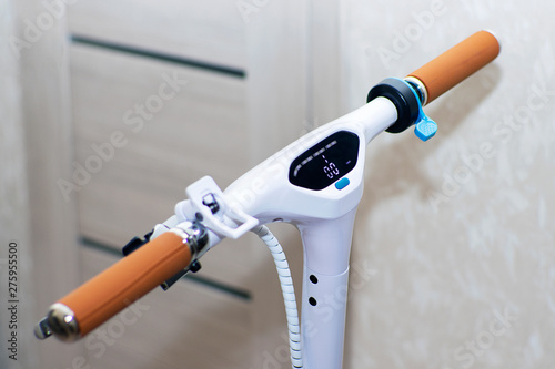 Electric scooter white with a control panel. Scooter steering wheel with brown leather handles. Blue lever accelerator.