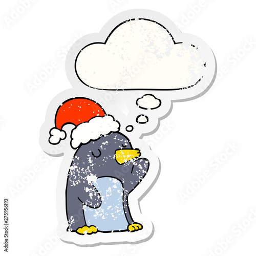 cute cartoon christmas penguin and thought bubble as a distressed worn sticker