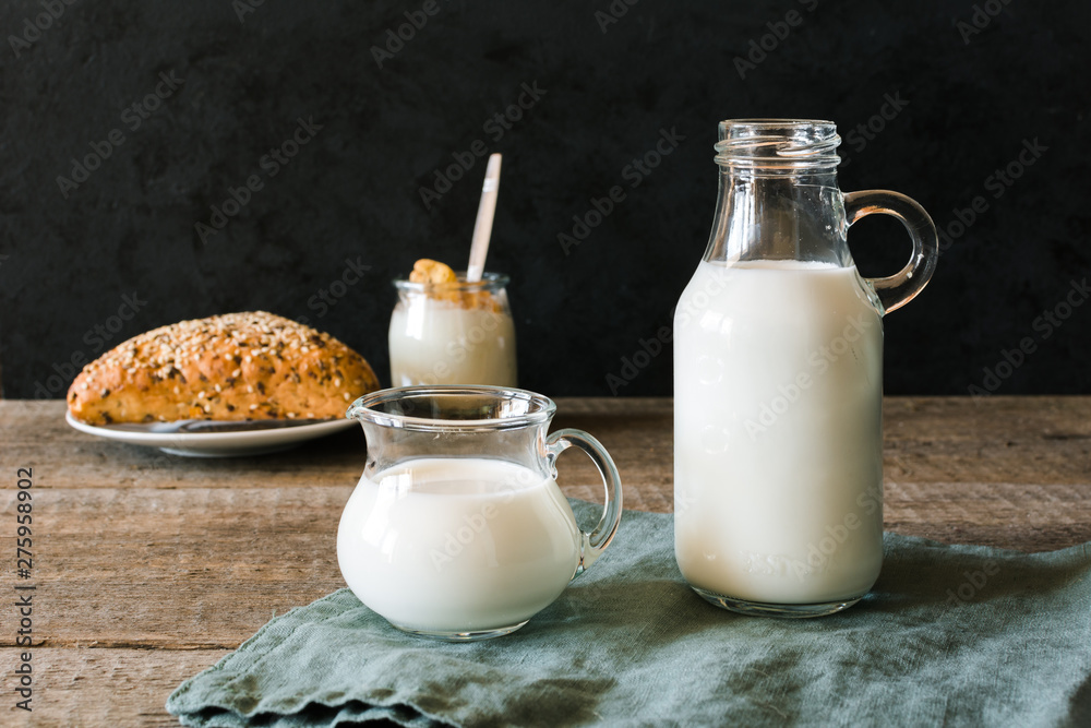 Dairy cuisine. A bottle of milk and glass of milk on a wooden table on a dark background