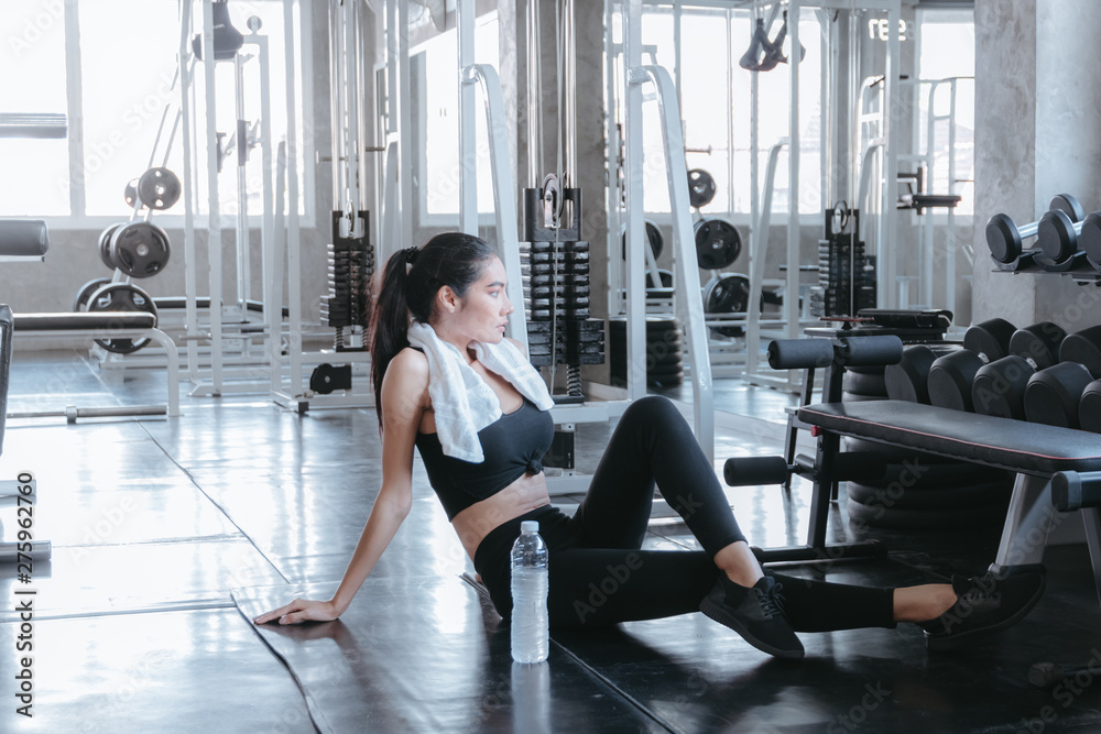 Fit young woman sitting on gym floor for relaxing with water bottle. Healthy and Exercise lifestyle Concept. Fit young woman sitting on gym floor for relaxing with water bottle. Healthy and Exercise lifestyle Concept.