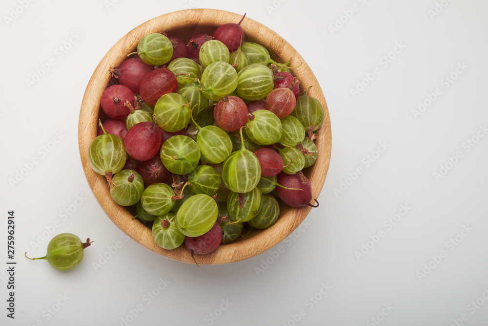 Gooseberries fruits on white background. Bowls with gooseberries isolated on white background. Red and green gooseberries in a bowl with copy space for text. Ripe gooseberry close-up. K Gooseberries fruits on white background. Bowls with gooseberries isolated on white background. Red and green gooseberries in a bowl with copy space for text. Ripe gooseberry close-up. K