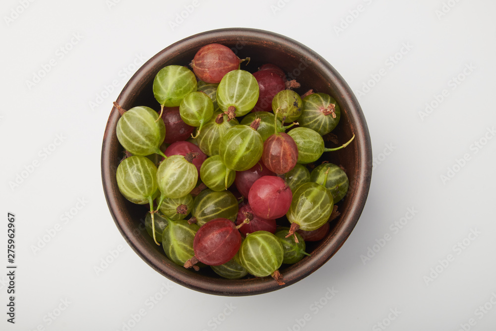 Gooseberries fruits on white background. Bowls with gooseberries isolated on white background. Red and green gooseberries in a bowl with copy space for text. Ripe gooseberry close-up. K Gooseberries fruits on white background. Bowls with gooseberries isolated on white background. Red and green gooseberries in a bowl with copy space for text. Ripe gooseberry close-up. K