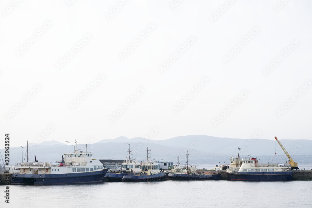 Ships and tug boats with crane in sea port dock
