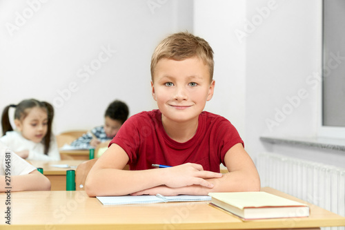 Male student sitting at desk with folded arms during lesson