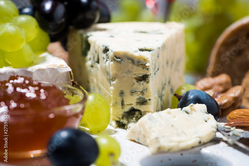fresh gourmet cheeses on a board, grapes and jams, closeup