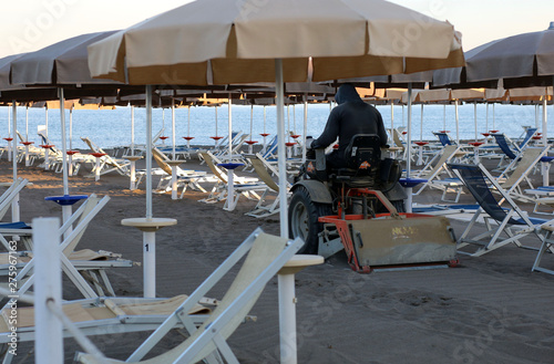 Operaio che pulisce al mattino la sabbia della spiaggia utilizzando una macchina filtrante photo