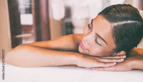 Luxury spa massage Asian woman relaxing lying down on table at hotel room. Massage therapy skincare beauty treatment.